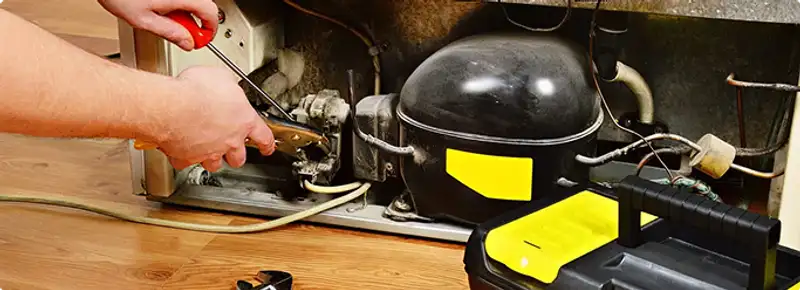 Refrigerator repair technician fixing the compressor and wiring in Loveland, CO