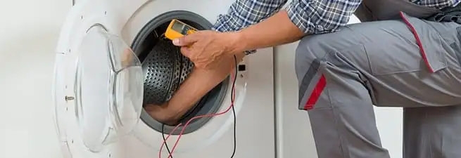Dryer repair technician inspecting and repairing a clothes dryer in Fort Collins, CO