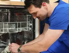 Dishwasher repair technician inspecting and servicing an open dishwasher in Fort Collins, CO