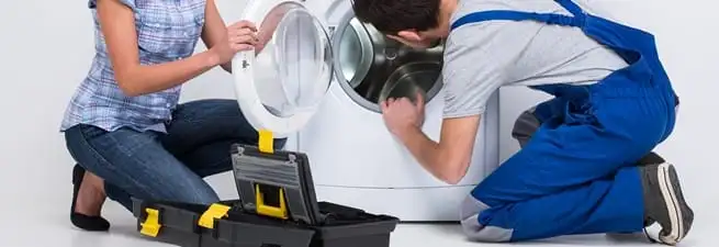 Washer repair technician inspecting a front-load washing machine with tools in Fort Collins, CO