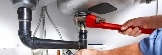 Garbage disposal repair technician tightening the sink drain and disposal connection in Fort Collins, CO