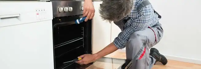 Oven repair technician inspecting and servicing an electric oven in Fort Collins, CO