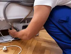 Appliance repair technician fixing refrigerator water line and connections in Fort Collins, CO