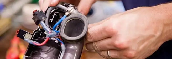 Vacuum repair technician reconnecting wiring and components in Fort Collins, CO