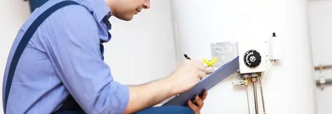 Water heater repair technician inspecting the unit and recording service notes in Fort Collins, CO
