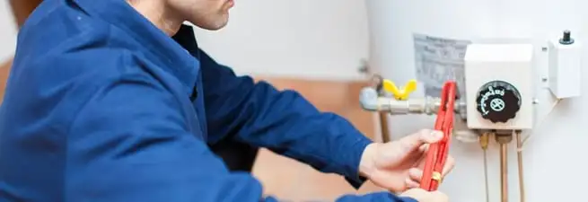 Water heater repair technician adjusting the temperature control and gas valve in Fort Collins, CO